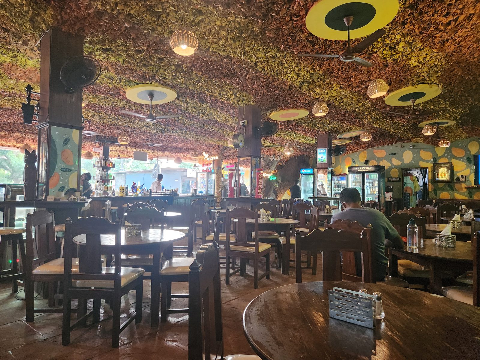 The wooden interior of a Goa restaurant with a tree growing up through it