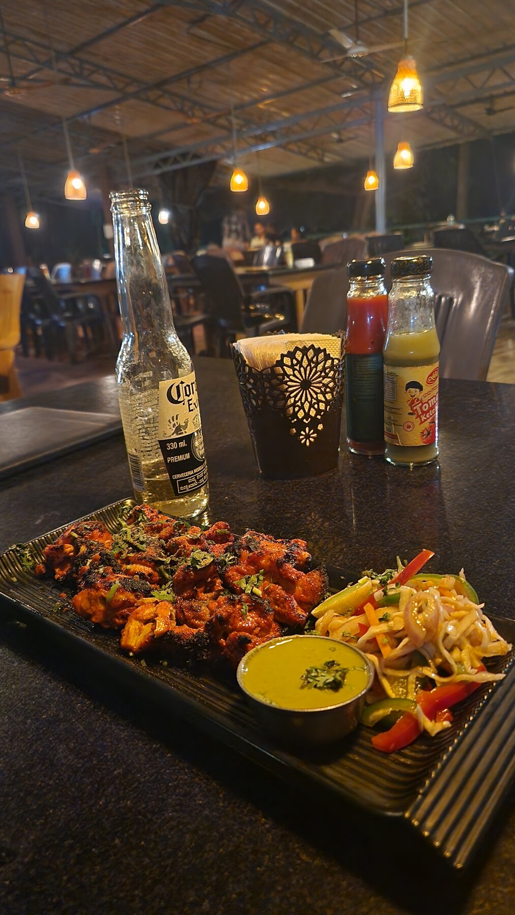 A plate of grilled chicken with chutney and salad and a Corona Extra at Namaste Cafe in Gokarna