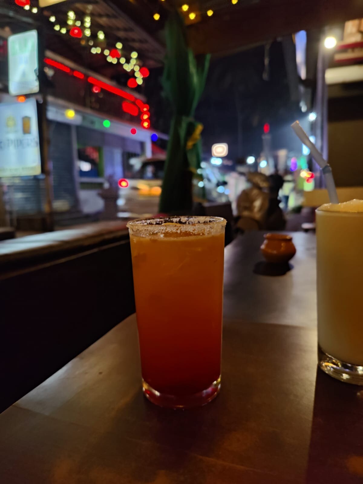 A tequila sunrise style cocktail and a pina colada on the bar table at Paulo's Bar