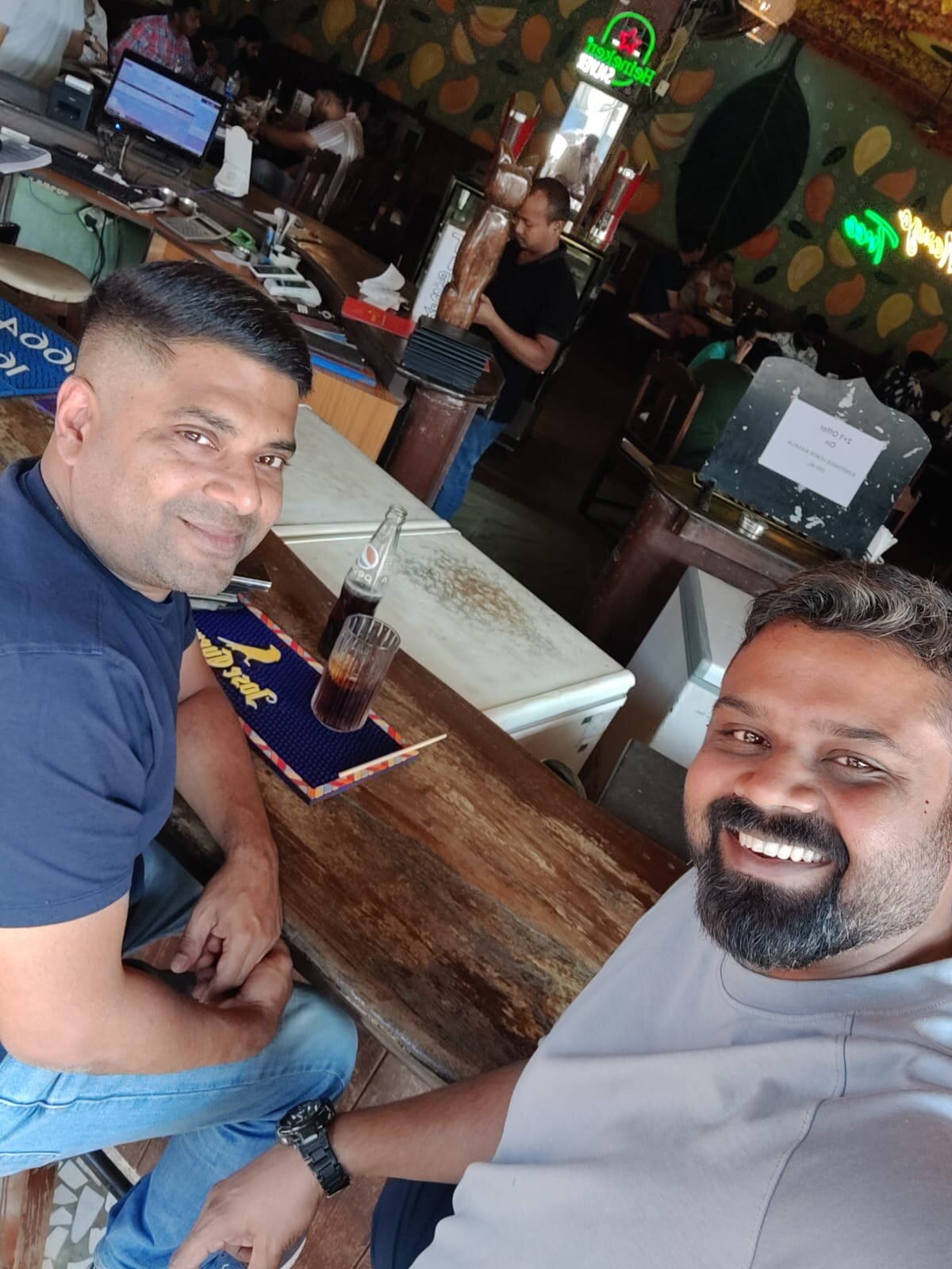 Two of us seated at the bar at Mango Tree in Vagator with a Pepsi bottle on the table