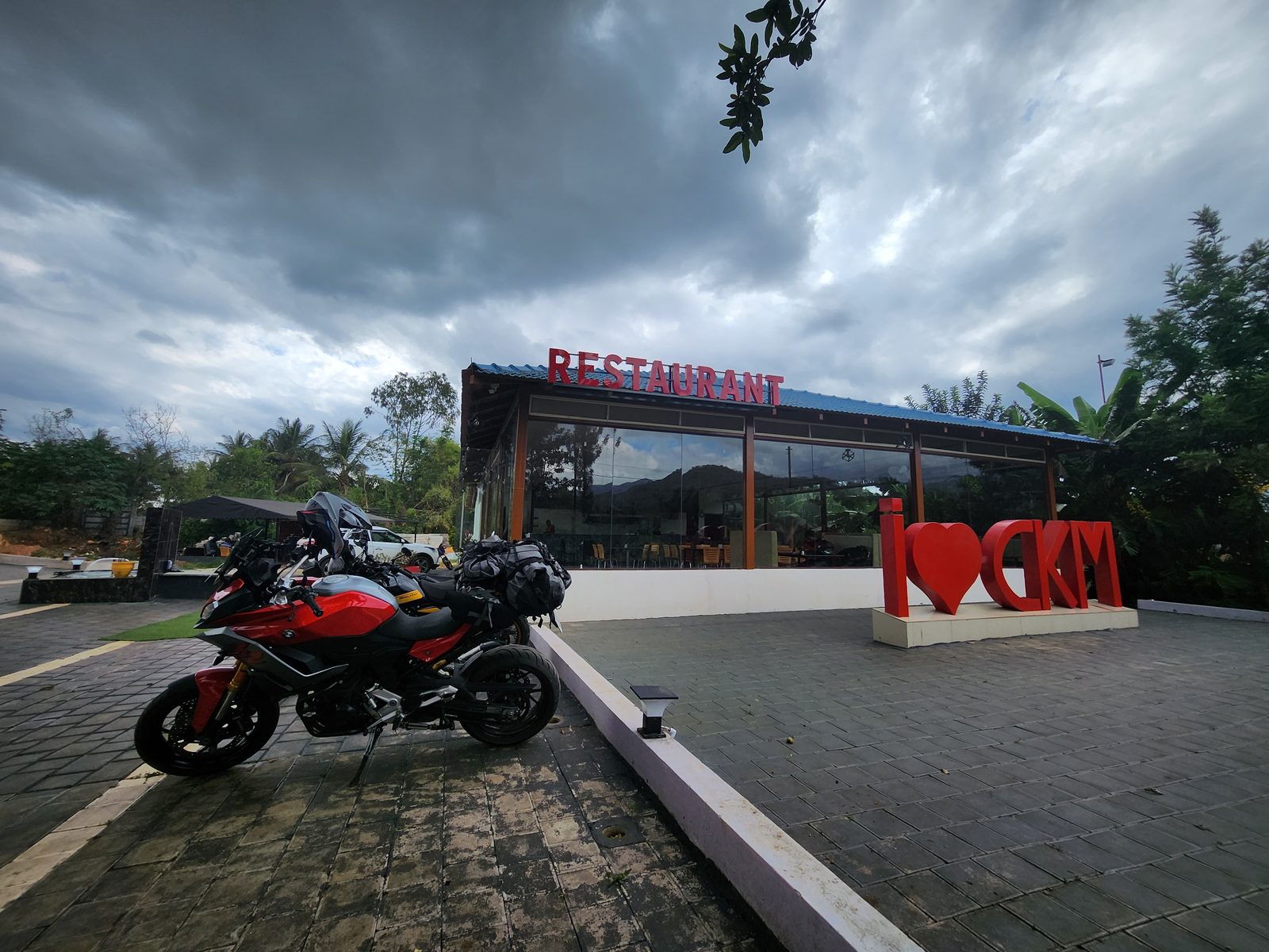 Both bikes outside a restaurant with an I love CKM sign, Chikkamagaluru