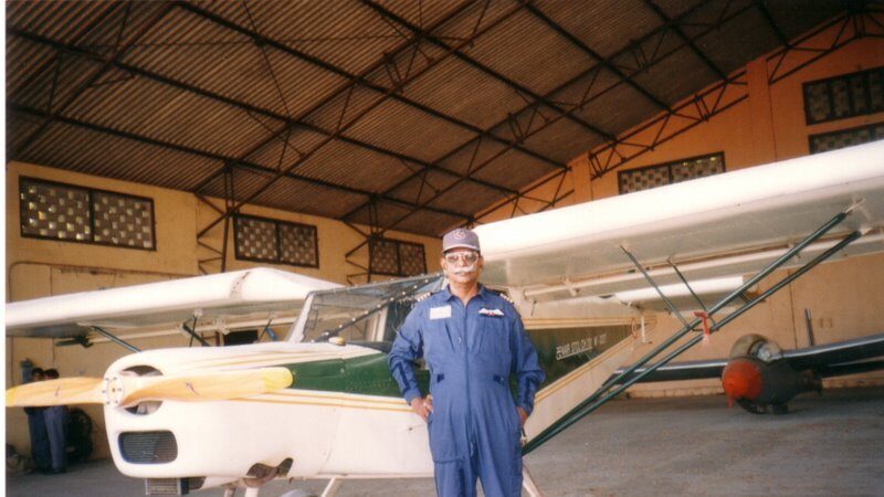 Captain Eugine Khan standing in the hangar in front of a training aircraft